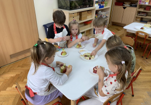 Przedszkolaki mocują w jabłku owocowe kolce.