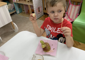 Chłopiec zjada owoce.