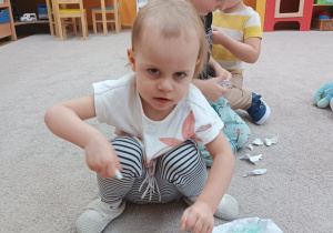 Dziewczynka rwie kartkę na małe kawałki