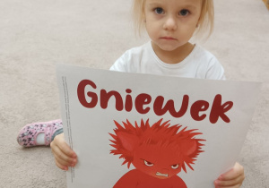 Dziewczynka pokazuje ilustrację Gniewka
