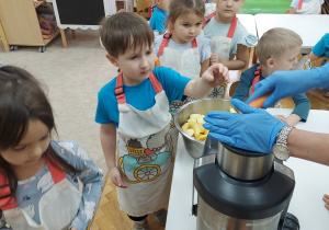 Dzieci wrzucają owoce do sokowirówki.