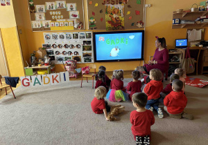 Dzieci z grupy 3 latków oglądają animację na tablicy multimedialnej.