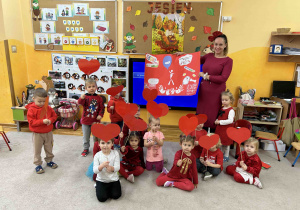 Dzieci z grupy 3 latków trzymają serduszka do wspólnego zdjęcia.