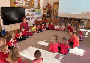 Dzieci z grupy 4 latków siedzą w kole na dywanie.