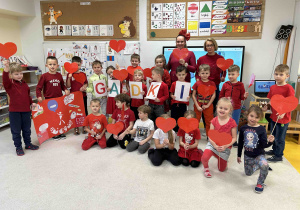 Dzieci z grupy 6 latków trzymają serduszka do wspólnego zdjęcia.