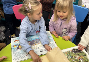 Dziewczynki porównują jak wygląda nowa i stara książka.