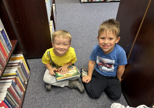 Chłopcy oglądają książki z literatury dziecięcej.