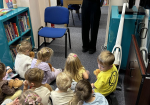 Czterolatki uważnie słuchają bajki czytanej przez p. bibliotekarkę.