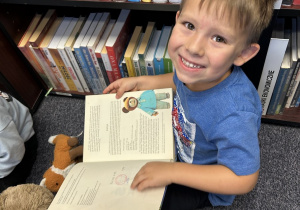 Chłopiec przegląda książkę pt. Miś Uszatek.