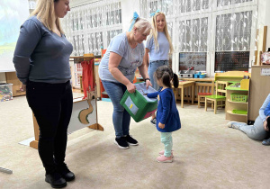 Dziewczynka wkłada rękę do pudełka.