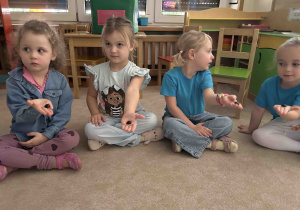 Dziewczynki trzymają w ręku kamyczki.