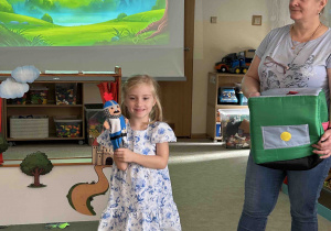 Dziewczynka stoi z pacynką na ręku.