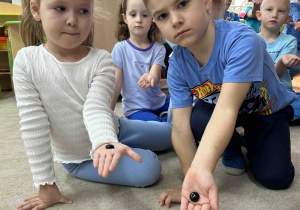 Dziewczynka i chłopczyk prezentują swoje kamyczki.