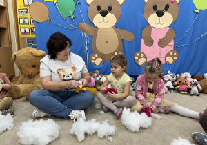 Pani pomaga wypełniać dzieciom misia.