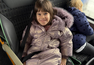Zadowolona dziewczynka wraca z wycieczki autobusem.