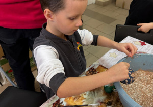 Chłopiec obsypuje bombkę brokatem.