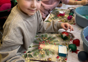 Chłopiec pokazuje ozdobioną bombkę.