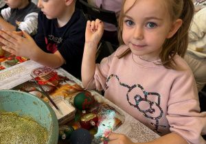 Dziewczynka pokazuje ozdobione bombki.