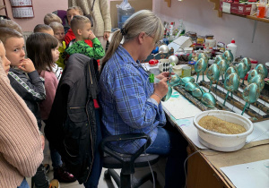 Dzieci obserwują jak pani ozdabia bombki.