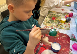 Chłopiec maluje bombkę.