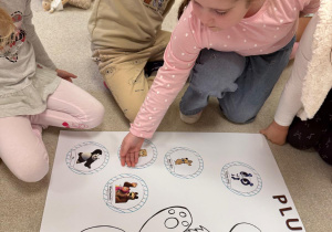 Dziewczynka przykleja misia na plakat.