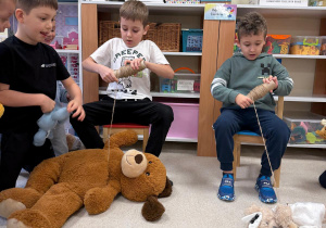 Dzieci biorą udział w zabawie "przyciągnij misia".