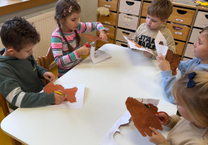 Dzieci wycinają misie przy stoliczku.