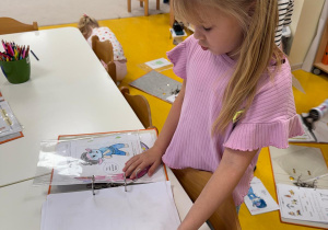 Dziewczynka uzupełnia książeczkę projektową.