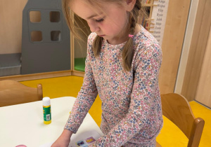 Dziewczynka uzupełnia książeczkę projektową.