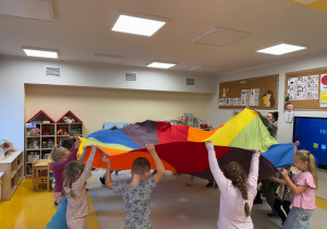 Dzieci unoszą wysoko chustę animacyjną.