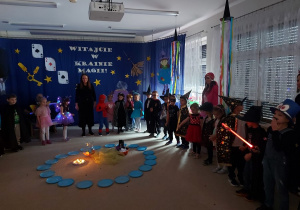 Dzieci przebrane w stroje stoją ustawione wokół magicznego kręgu.