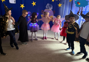 Dzieci ubrane w stroje tańczą na balu.