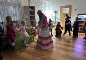 Dzieci pod okiem cyganki uczestniczą w zabawie z hula hop.