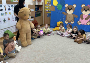 Dzieci oglądają maskotkę misia.