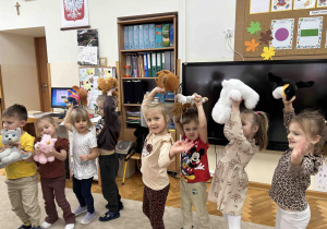 Dzieci machają misiami.