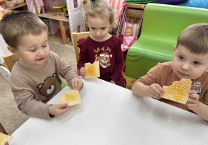 Dzieci jedzą wafelki z miodkiem.