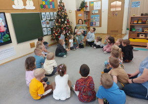 Dzieci siedzą w kole i słuchają bajki czytanej przez mamę Frania.