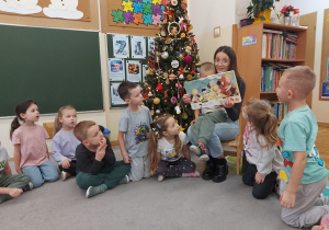 Czytający rodzic pokazuje dzieciom ilustrację z czytanej książki.