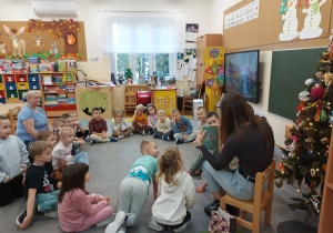 Dzieci siedzą w kole i uważnie słuchają bajki.