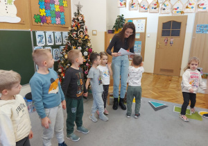 Dzieci wręczają rodzicowi podziękowanie z rysunkami przedszkolaków.