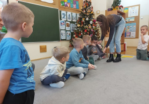 Pani wręcza dzieciom cukierka.