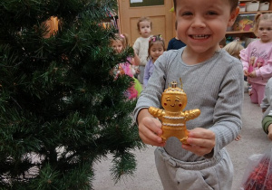 01. Chłopiec zawiesza pierniczka na choinkę.