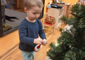 04. Chłopiec zawiesza bombki na choinkę.