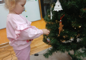 06. Dziewczynka zawiesza bałwanka na choinkę.