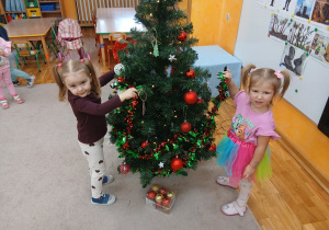 19. Dziewczynki zawieszają łańcuch na choinkę.