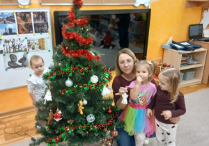 20. Pani zawiesza aniołka na choinkę.