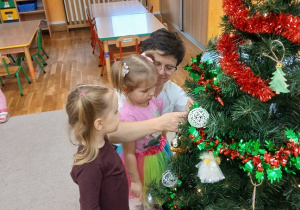 21. Pani zawiesza aniołka na choinkę.