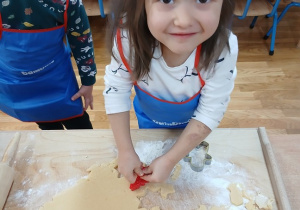 09. Dziewczynka wykrawa ciasteczko w kształcie choinki.