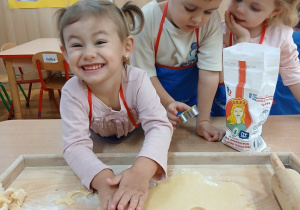 15. Uśmiechnięta dziewczynka wykrawa ciasteczka.