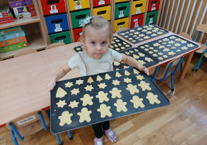 20. Dziewczynka trzyma blaszkę z ciasteczkami.